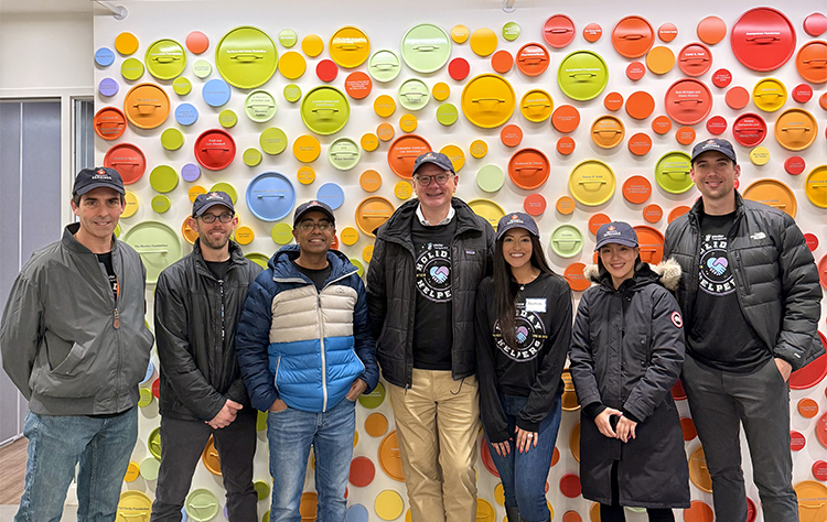 Group of employees standing in front of colorful wall.